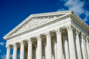 Naklejka premium Crisp blue sky view of the neoclassical white marble exterior of the United States Supreme Court Building in Washington DC, USA
