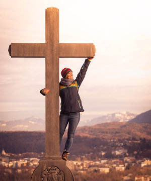 Young girl stands proud and happy on a summit cross, autumn