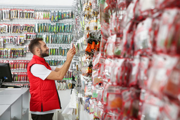 Salesman showing fishing equipment in sports shop