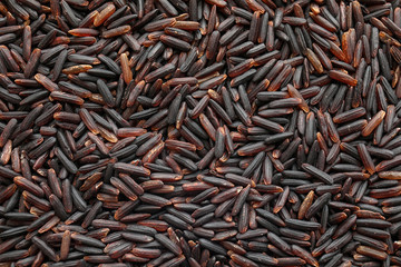 Uncooked black rice as background, top view