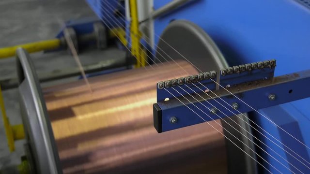Industrial cable production. Part of production equipment. Copper wire is strung like a string. Shop drawing and stranding twist. Productions of flexible multicore cable.