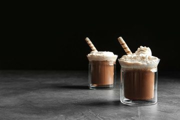 Glasses with delicious coffee drink on grey table against black background. Space for text
