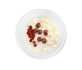 Creamy rice pudding with red currant and hazelnuts in bowl on white background, top view