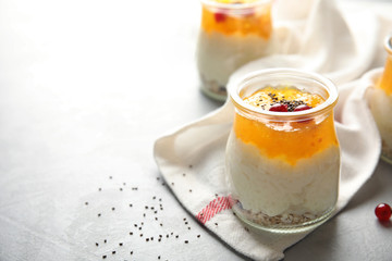 Creamy rice pudding with red currant, jam and oatmeal in jar on table. Space for text