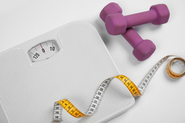 Naklejka premium Modern scales, tape measure and dumbbells on white background