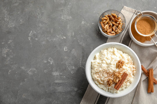 Creamy rice pudding with cinnamon and walnuts in bowl served on grey table, top view. Space for text