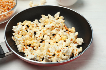 Frying pan with tasty popcorn on table