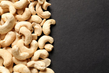 Fototapeta na wymiar Tasty cashew nuts on black background, top view. Space for text