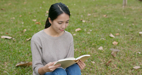 Woman read book and sitting on green grass