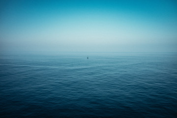 Meer mit kleinem Boot auf hoher See bei blauem Himmel