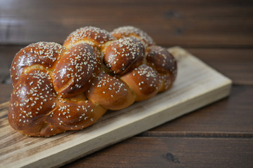 Traditional Jewish sweet Challah bread on a wood plate on wooden table / background with copy space