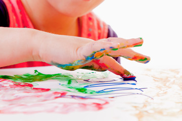 Child girl painting with colorful hands and finger. Happy childhood, art, drawing concept.
