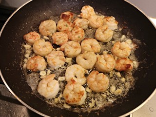 Cooking shrimps with butter in a black pan