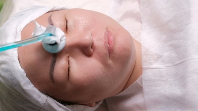 A girl of Asian appearance in a beauty salon. Hardware cosmetology. Darsonvalization. Modern cosmetology procedure for cleansing and rejuvenation of the skin.