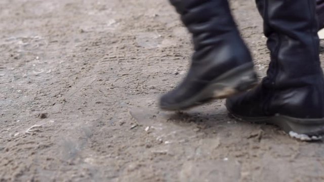 Close-up of feet of crowd of people in city. Crowds of human feet trample on dirty snow in city in winter. Urban movement of people