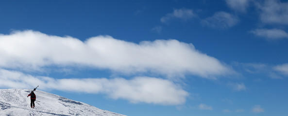 Fototapeta na wymiar Blue sky and skier with skis go up to top of mountain