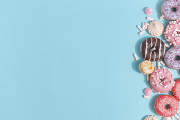 Composition of sweet glazed donuts and sweets on a blue background. Top view. Concept of children's holiday. Space for copy.