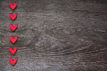 The red hearts are arranged vertically on the left on an old wooden brown dry board. Valentine's Day Card