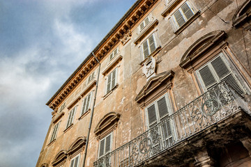 An ancient palace ruined by time, in the center of Anagni, Frosinone, Italy. Balcony with iron railing, windows with marble frames and decorations and wooden shutters.