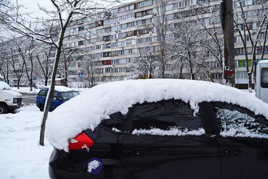View of the black car in the snow in the city in winter.