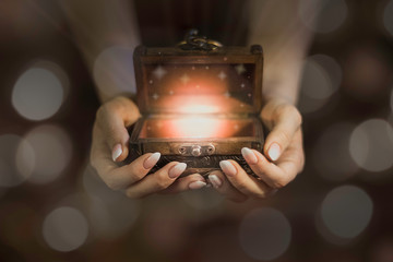 opened wooden magic box on hands, lights from little chest, dreams in hands, believe in miracle