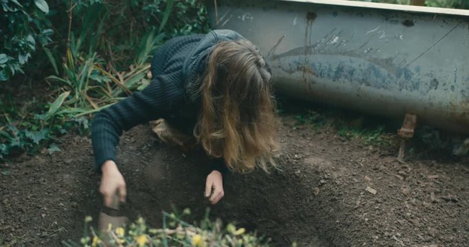 Young woman digging hole by a bathtub