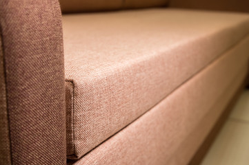 A close-up of a fragment of an expensive beige textile sofa in the room