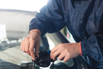 Close-up of a professional windshield repairman working with hydraulic polymer crack filler. Elimination of cracks and chips on windshields