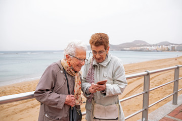 Two old women looking a smartphone screen.