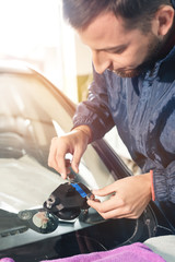 Close-up of a professional windshield repairman working with hydraulic polymer crack filler....