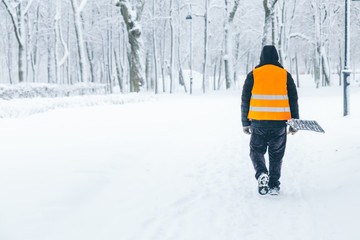 janitor with shovel in the park in winter