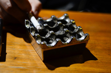 he takes a cigarette from a traditional ashtray