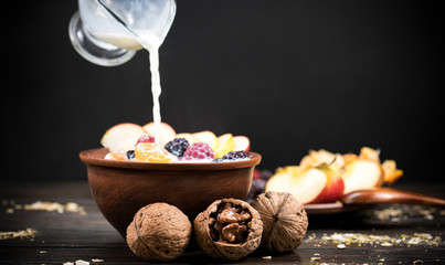 To a portion of tasty, healthy oatmeal with blackberry slices, raspberries and tangerines add a portion of fresh milk. Healthy food. Breakfast