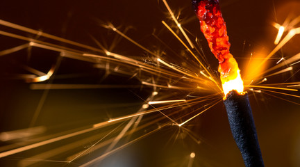 Flaming sparkler on red background close up macro