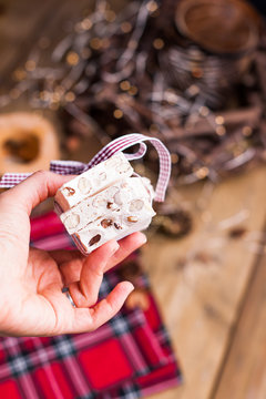 Traditional Italian sweet from nougat and almond for Christmas. Candy in a female hand. Free space for text.