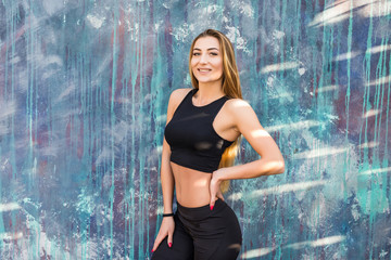 Young beautiful fitness woman wearing sporty clothes tanding against wall. Fitness workout concept.