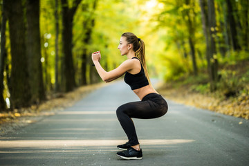 Fototapeta na wymiar Young woman make squat fitness exercises in park