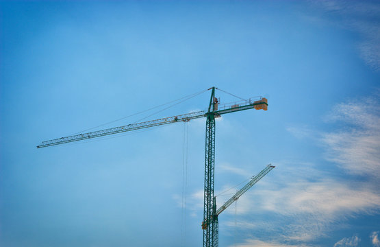 Two tower cranes on cloud and blue sky background