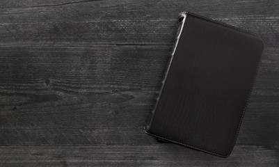 A Single Black Bible Laid Out on a Black Wooden Table