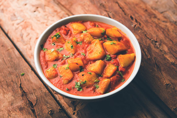 Indian food - Aloo curry masala. Potato cooked with spices and herbs in a tomato curry. served in a bowl over moody background. selective focus