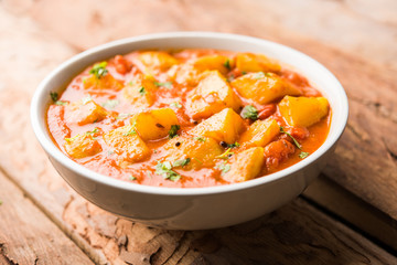 Indian food - Aloo curry masala. Potato cooked with spices and herbs in a tomato curry. served in a bowl over moody background. selective focus