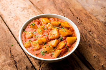 Indian food - Aloo curry masala. Potato cooked with spices and herbs in a tomato curry. served in a bowl over moody background. selective focus
