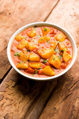 Indian food - Aloo curry masala. Potato cooked with spices and herbs in a tomato curry. served in a bowl over moody background. selective focus