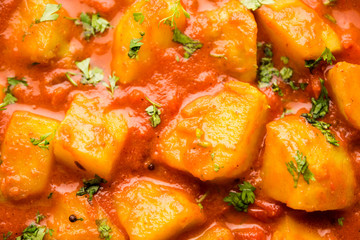 Indian food - Aloo curry masala. Potato cooked with spices and herbs in a tomato curry. served in a bowl over moody background. selective focus