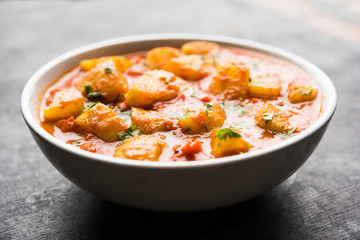 Indian food - Aloo curry masala. Potato cooked with spices and herbs in a tomato curry. served in a bowl over moody background. selective focus