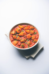 Indian food - Aloo curry masala. Potato cooked with spices and herbs in a tomato curry. served in a bowl over moody background. selective focus