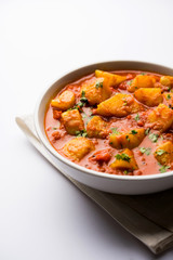 Indian food - Aloo curry masala. Potato cooked with spices and herbs in a tomato curry. served in a bowl over moody background. selective focus