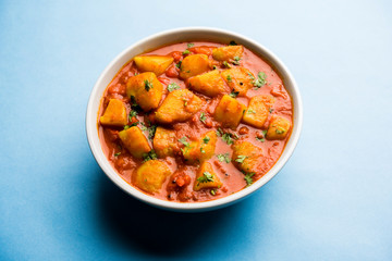 Indian food - Aloo curry masala. Potato cooked with spices and herbs in a tomato curry. served in a bowl over moody background. selective focus