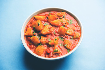 Indian food - Aloo curry masala. Potato cooked with spices and herbs in a tomato curry. served in a bowl over moody background. selective focus