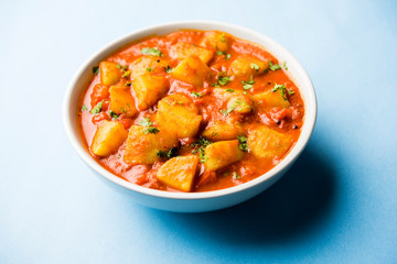 Indian food - Aloo curry masala. Potato cooked with spices and herbs in a tomato curry. served in a bowl over moody background. selective focus